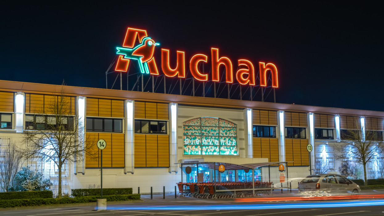 Roncq,FRANCE-February 27,2019: Night view of Auchan supermarket logo, entrance and parking.Auchan is a French international supermarket chain, is one of the largest distribution groups in the world.