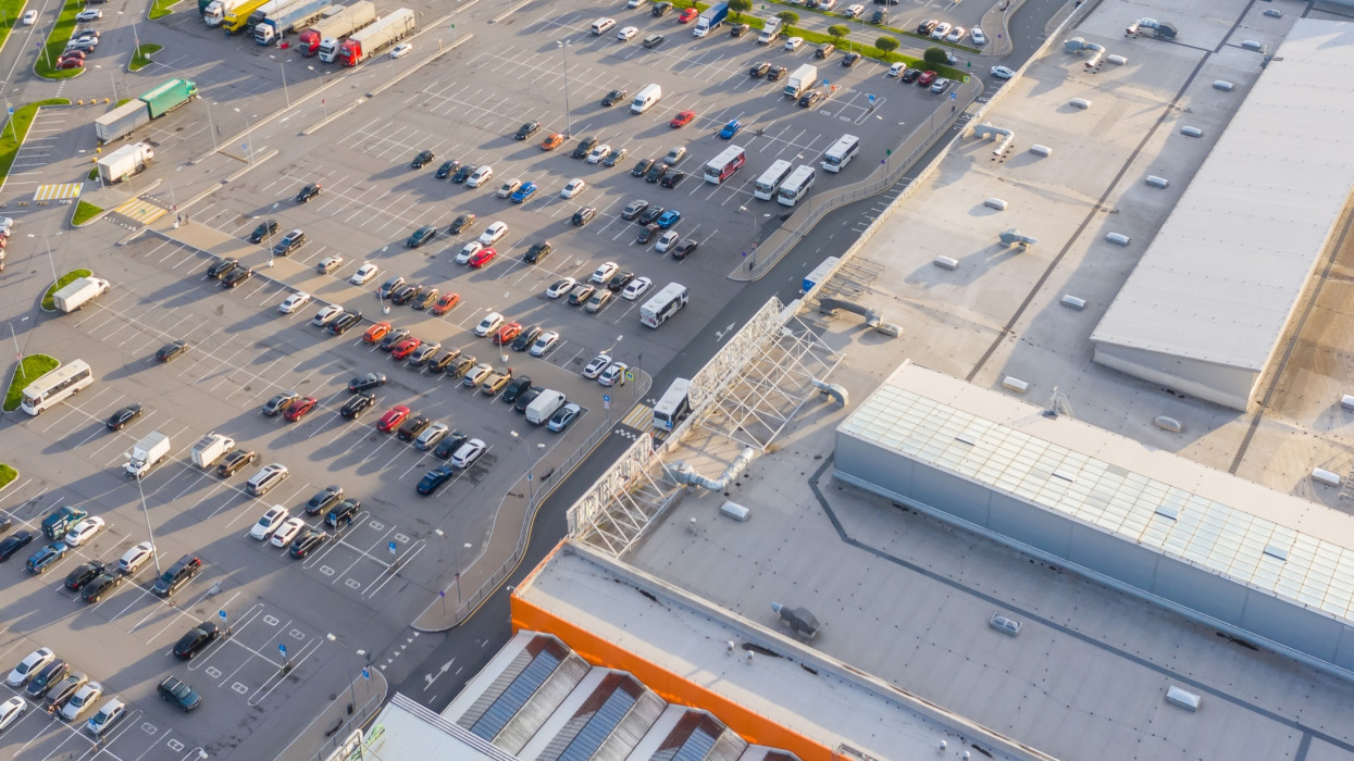 Aerial top down view of the parking lot with many cars of supermarket shopping center shoppers in the city grocery store